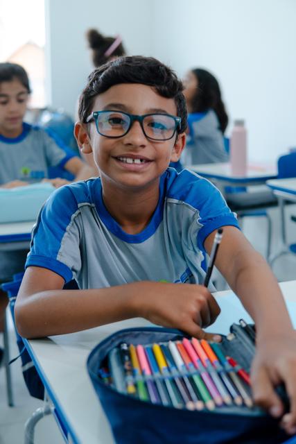 Aluno de óculos sorrindo na sala de aula