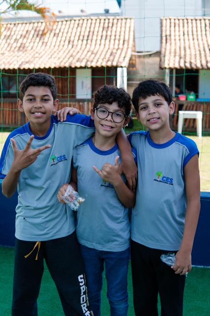 Três alunos abraçados na quadra