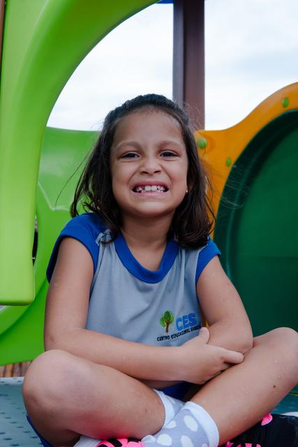 Aluna sorrindo sentada no parquinho