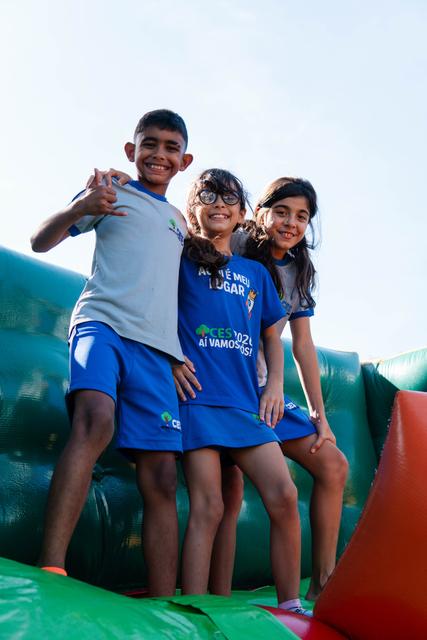 Três alunos sorrindo no brinquedo inflável